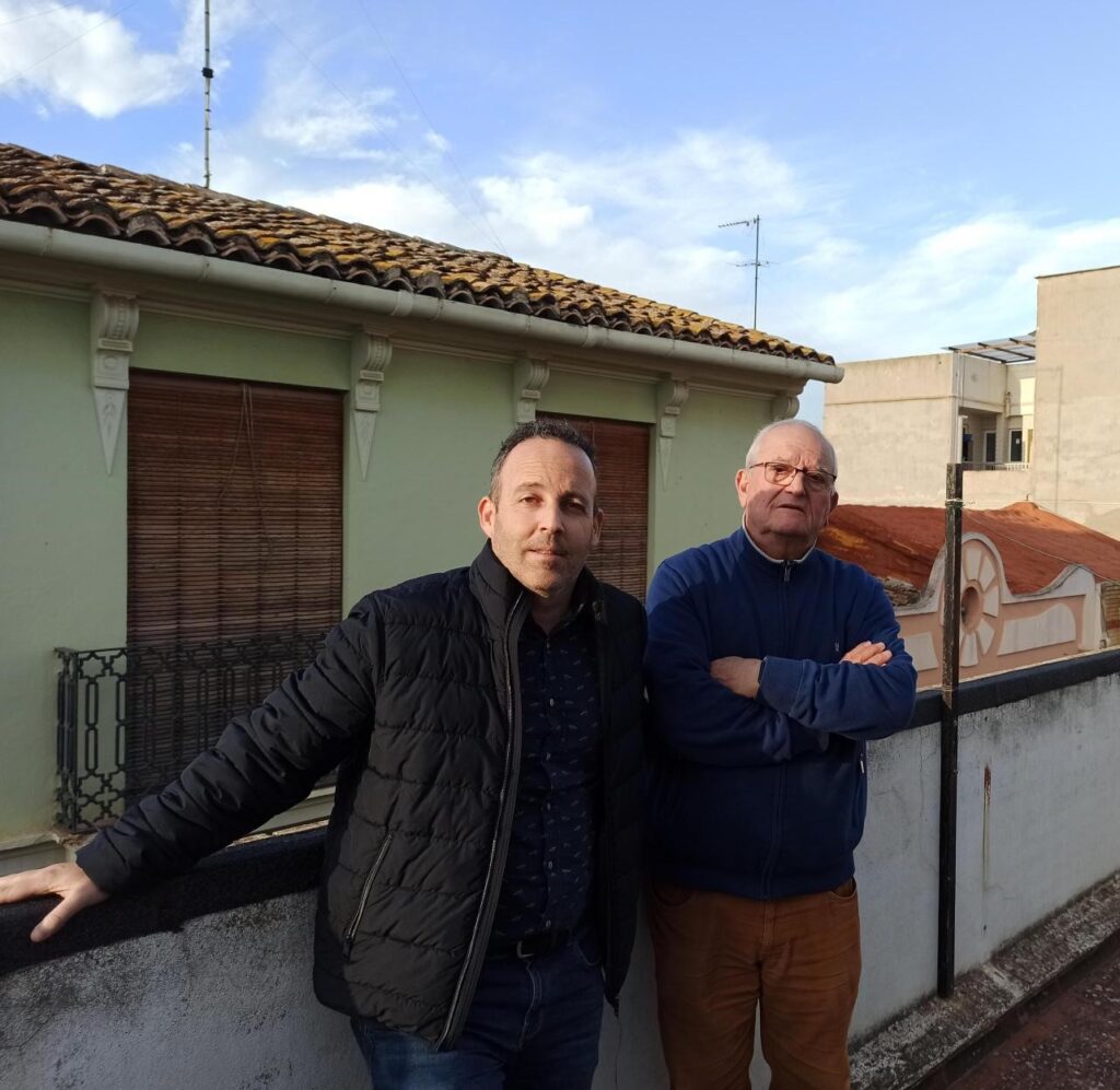 Salvador y Claudio posan en la terraza del primero, viendo cómo se instala su nuevo autoconsumo colectivo
